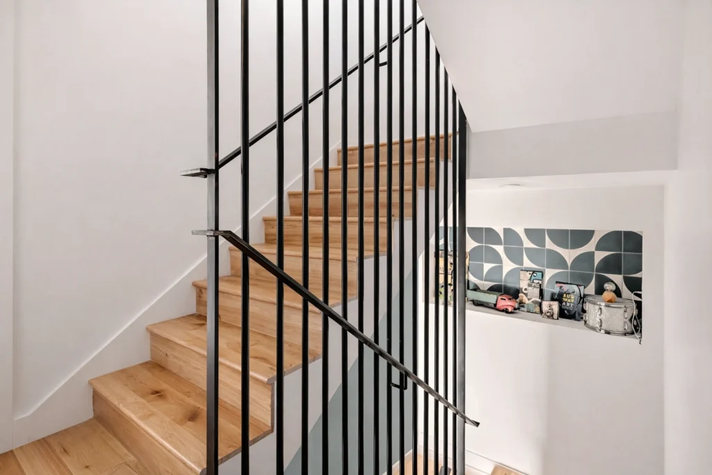 Contemporary staircase with black metal railing and natural wood stairs