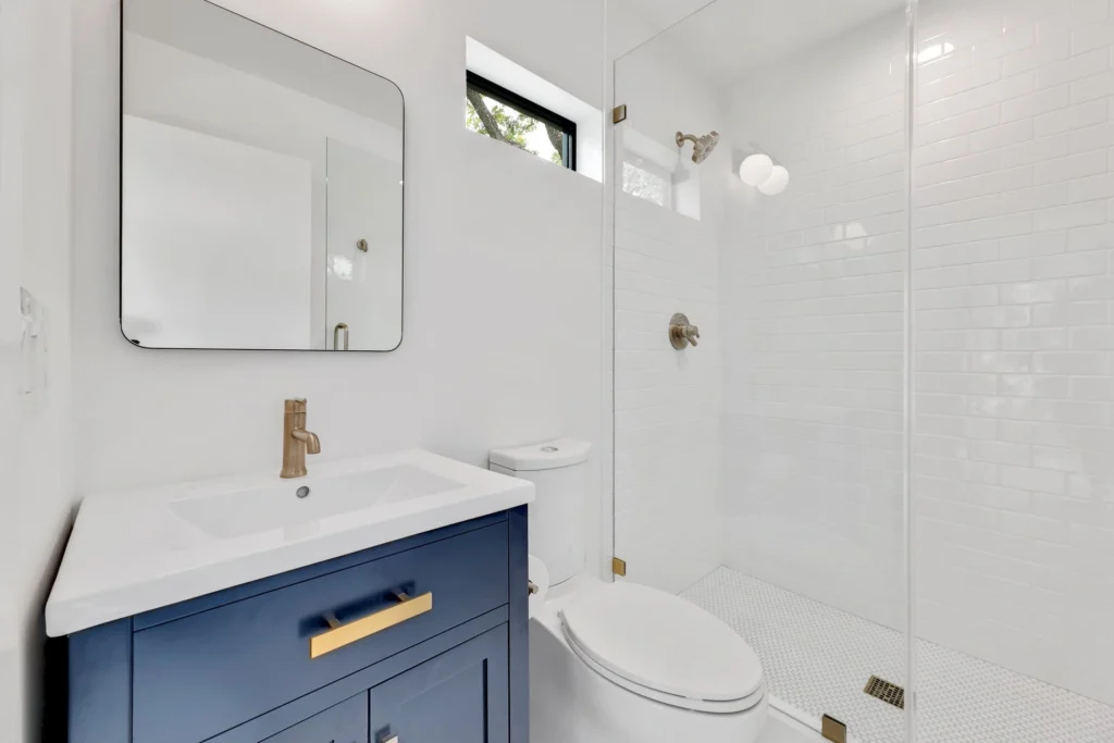 Minimalist bathroom remodel with blue vanity and white tile shower