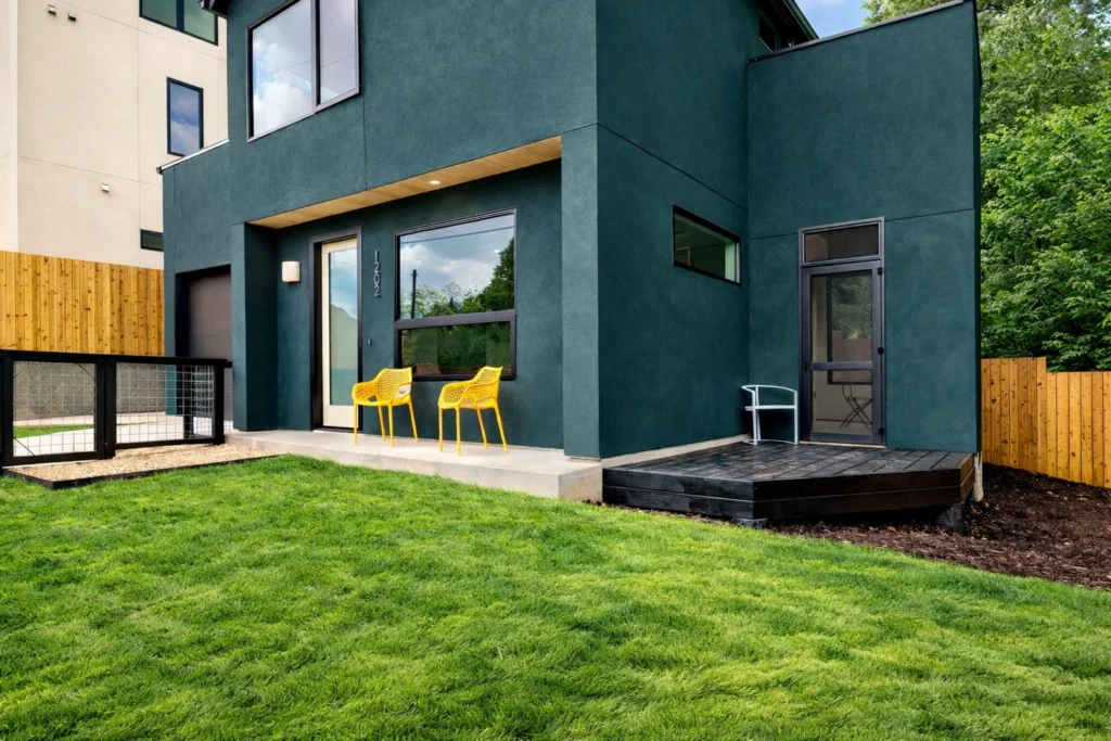 Modern dark green home exterior with landscaped backyard
