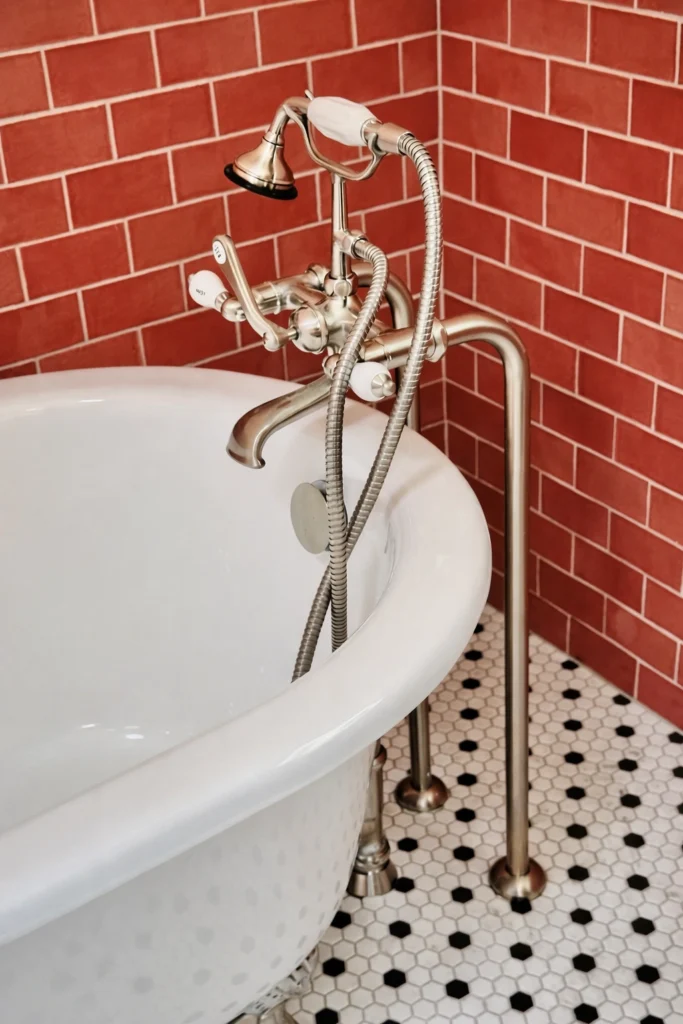 Freestanding soaking tub with coral tile surround and mosaic flooring