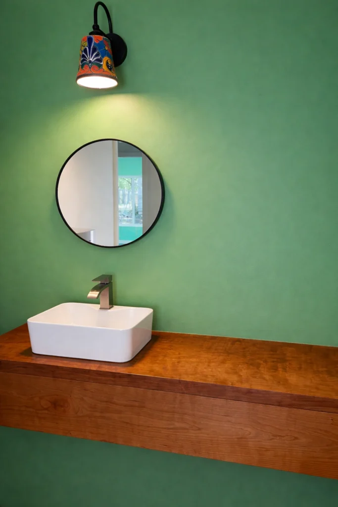 Minimalist powder bathroom with green accent wall and floating wood vanity