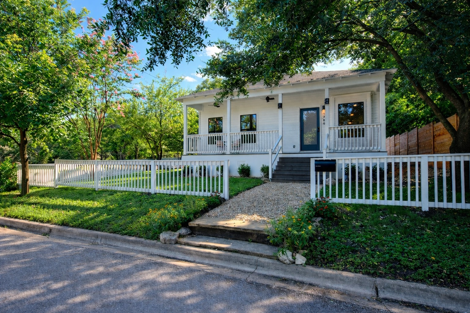 Modern white custom home exterior with covered front porch and white picket fence in Austin Texas