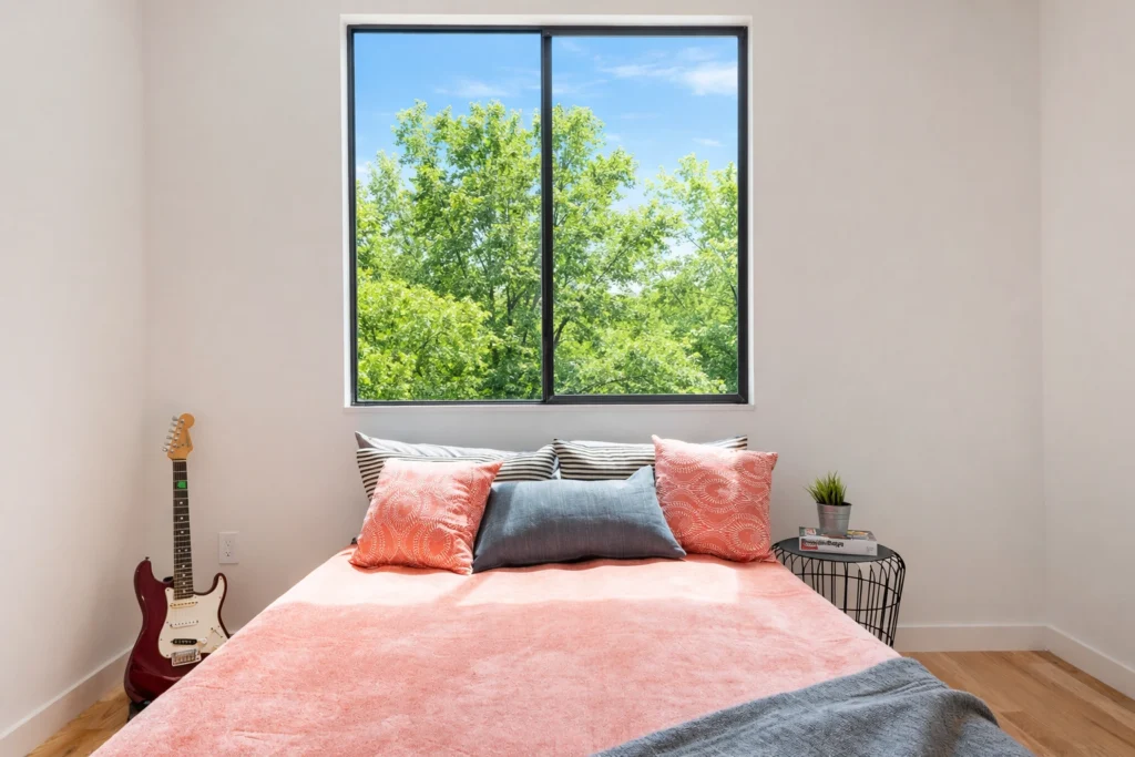 Minimalist bedroom with large black-framed window and natural light