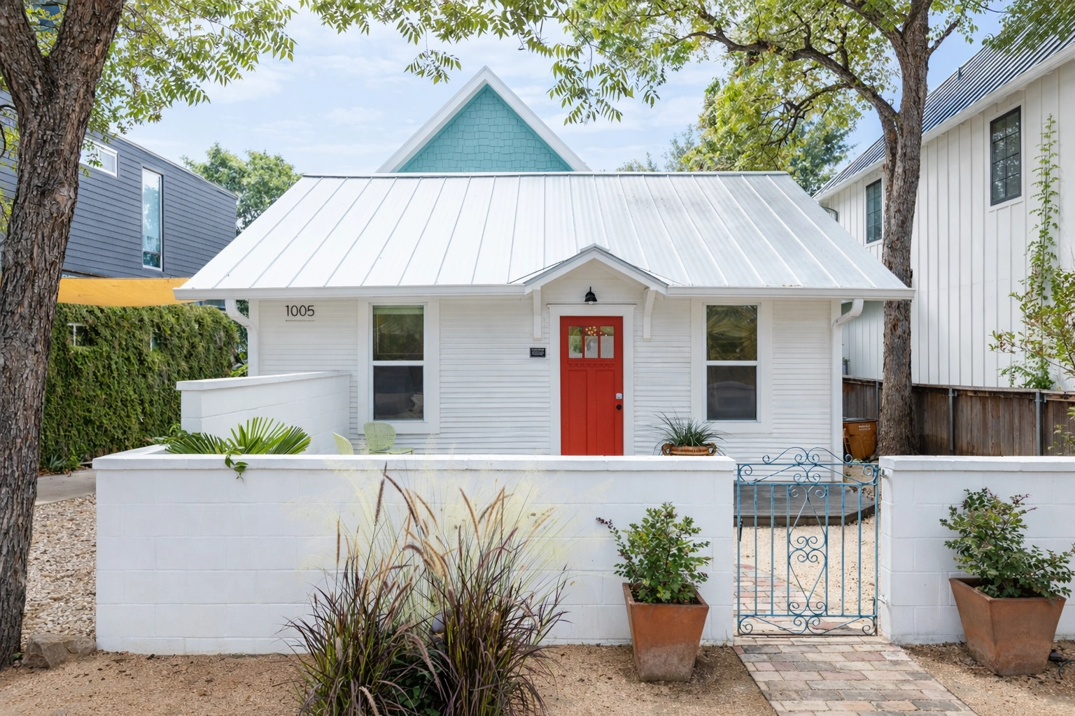 White cottage-style home with red front door and metal roof