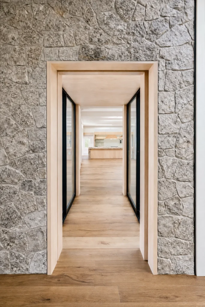 Minimalist architectural hallway with stone walls and oak flooring