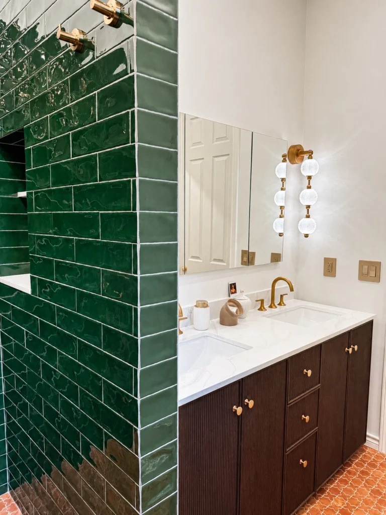 Green tile shower and custom walnut vanity with brass fixtures in an Austin bathroom remodel by Dwell Best Construction.
